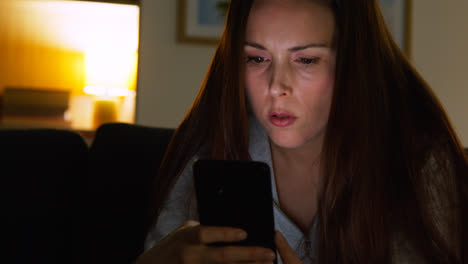 Anxious-Woman-Sitting-On-Sofa-At-Home-At-Night-Looking-At-Mobile-Phone-Concerned-About-Social-Media-Or-Bad-News-3